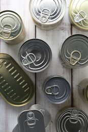 Photo of Many closed tin cans on white wooden table, flat lay