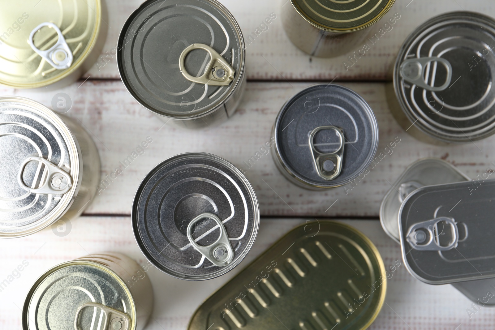 Photo of Many closed tin cans on white wooden table, flat lay