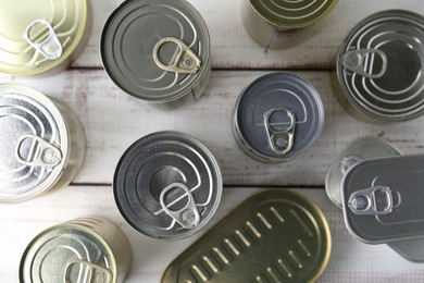 Photo of Many closed tin cans on white wooden table, flat lay