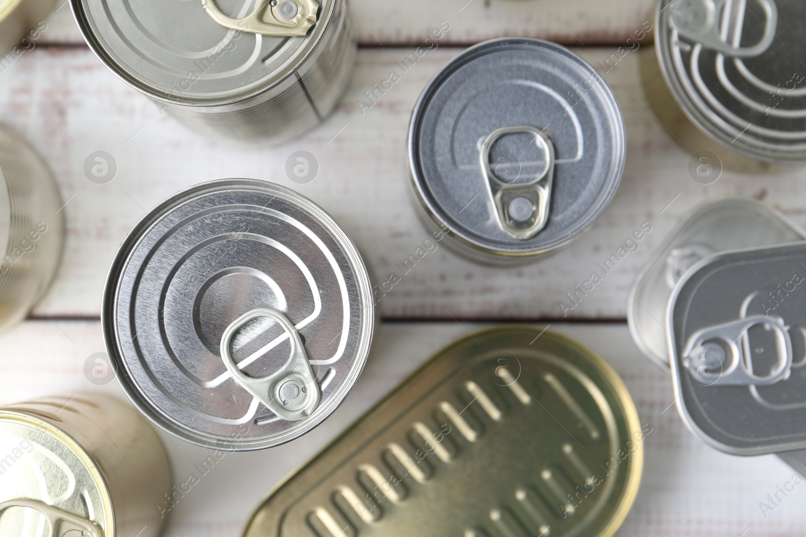 Photo of Many closed tin cans on white wooden table, flat lay