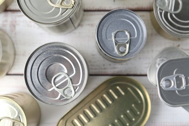 Photo of Many closed tin cans on white wooden table, flat lay