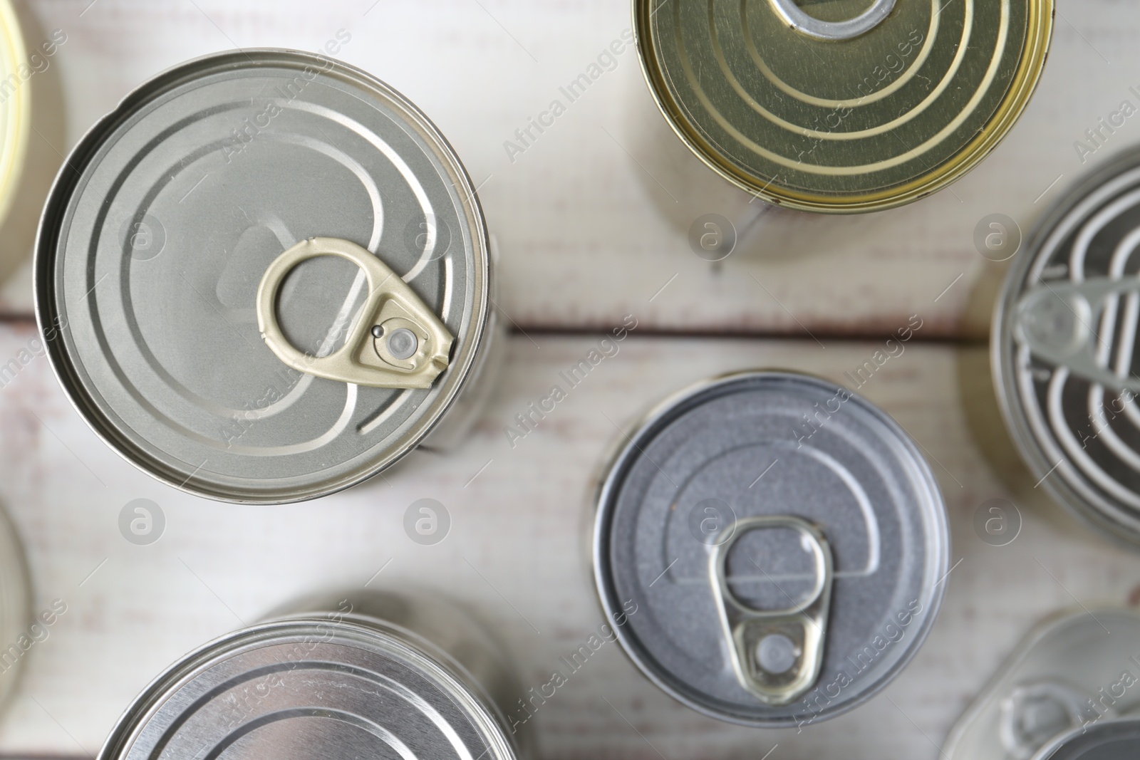 Photo of Many closed tin cans on white wooden table, flat lay