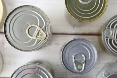 Photo of Many closed tin cans on white wooden table, flat lay