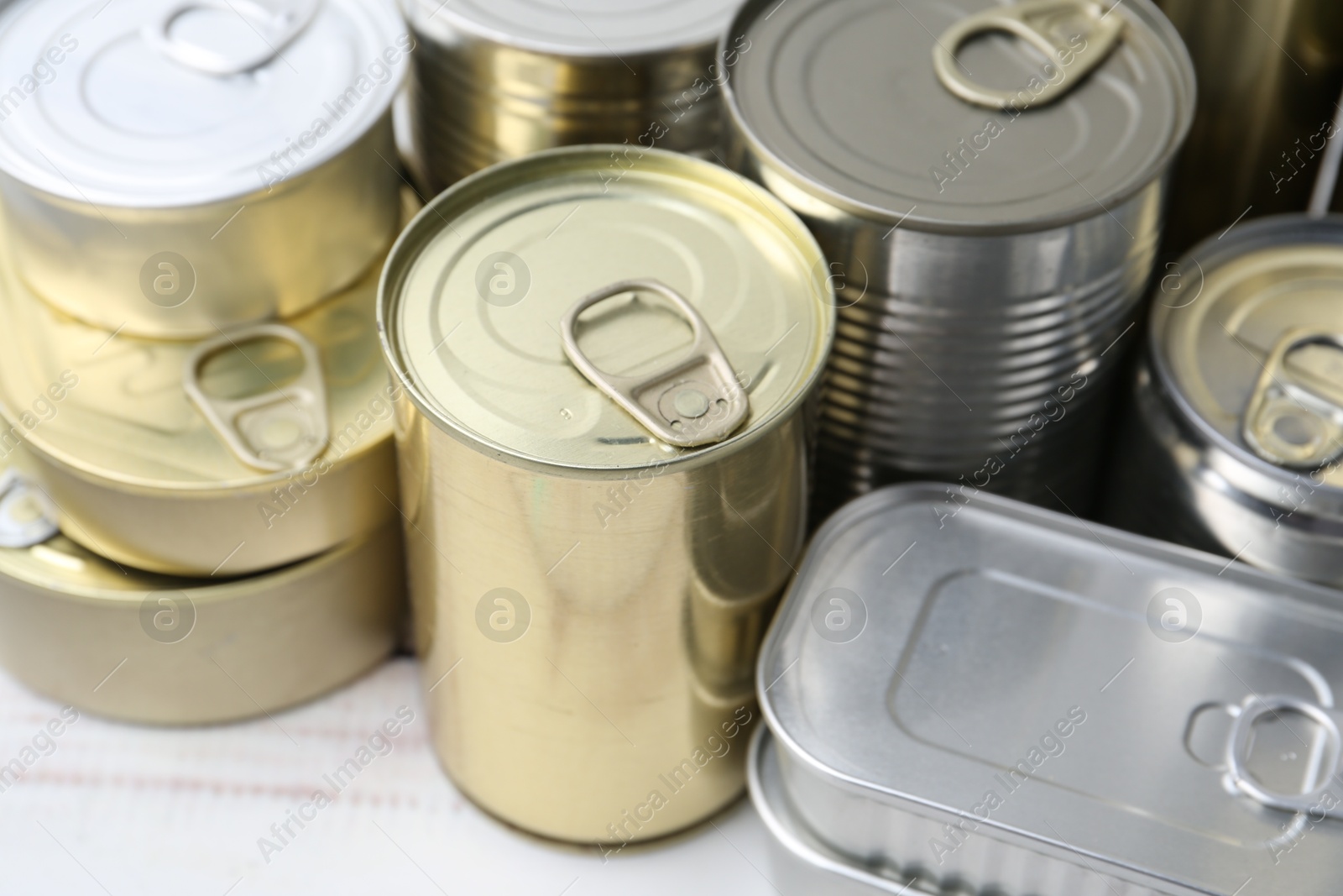 Photo of Many closed tin cans on white wooden table, closeup