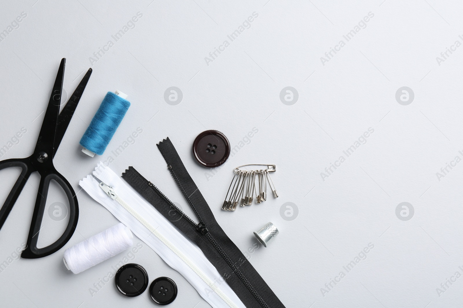 Photo of Different sewing supplies on white background, flat lay. Space for text