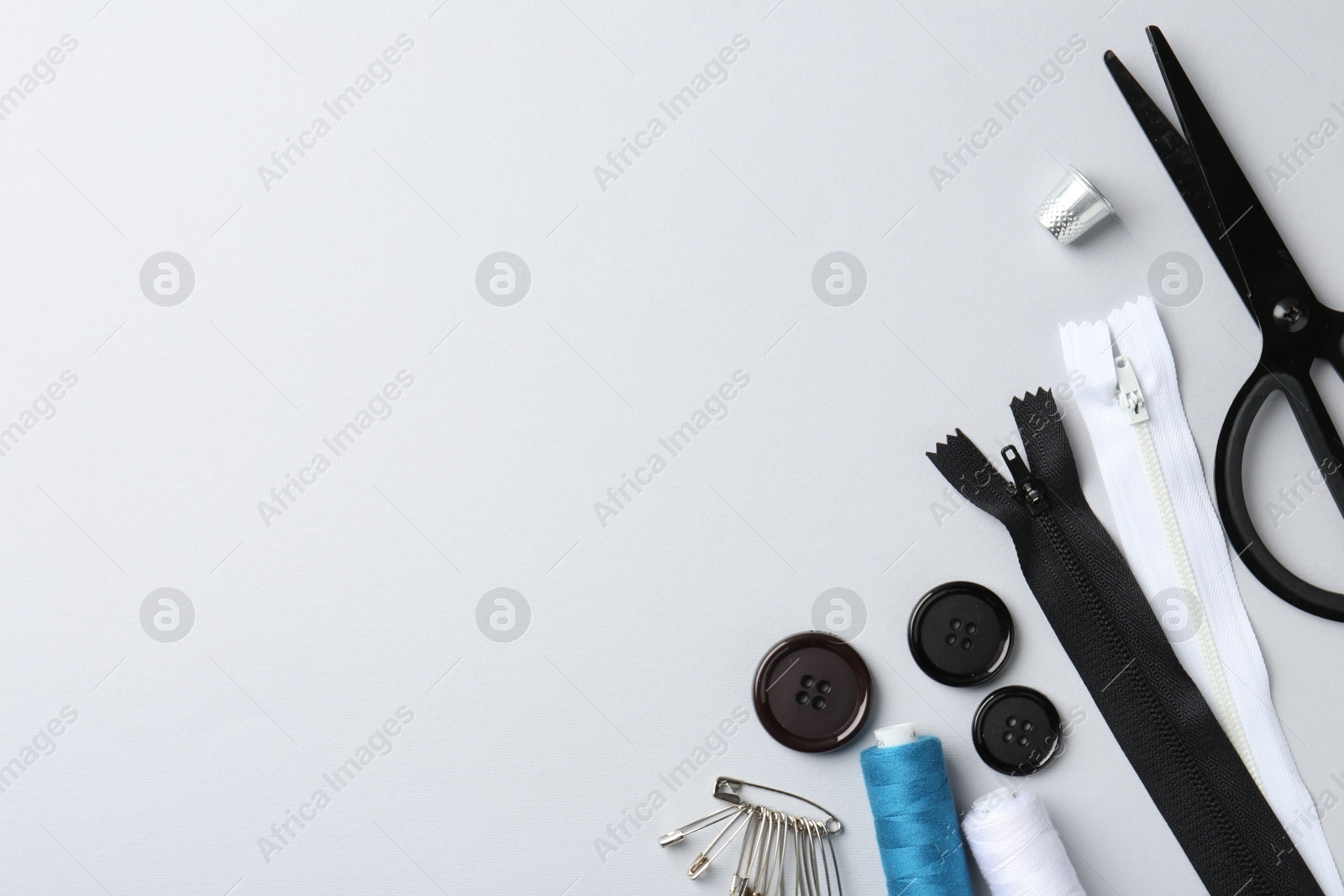 Photo of Different sewing supplies on white background, flat lay. Space for text