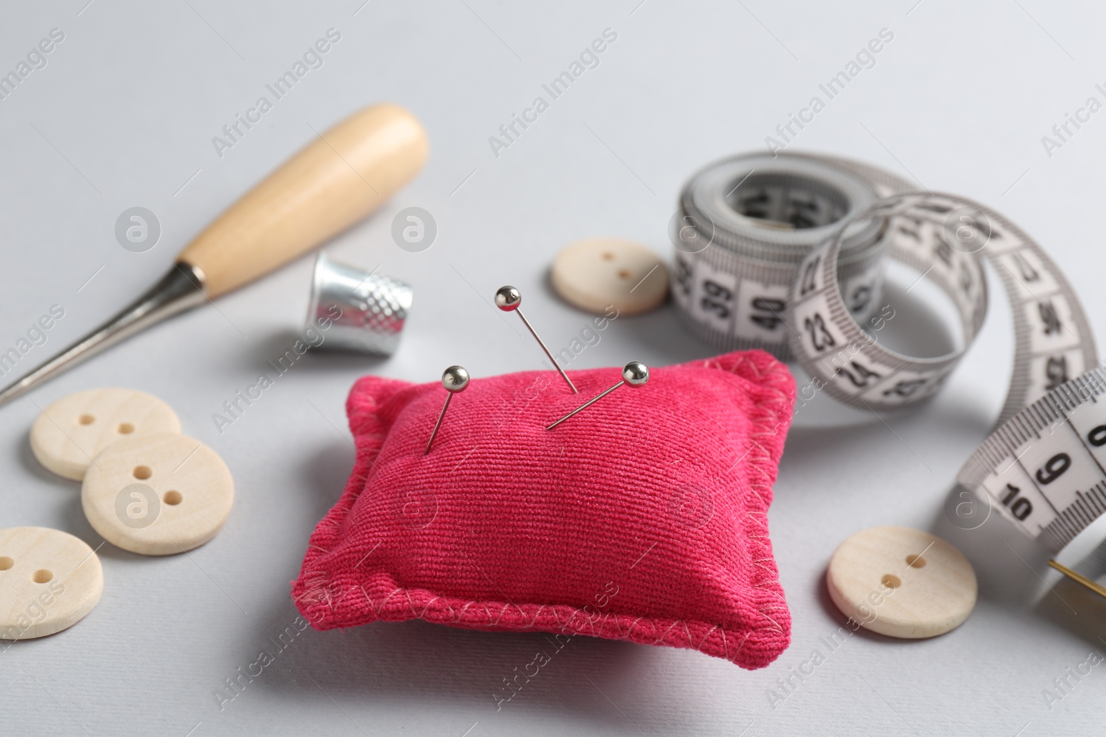 Photo of Different sewing supplies on light grey background, closeup