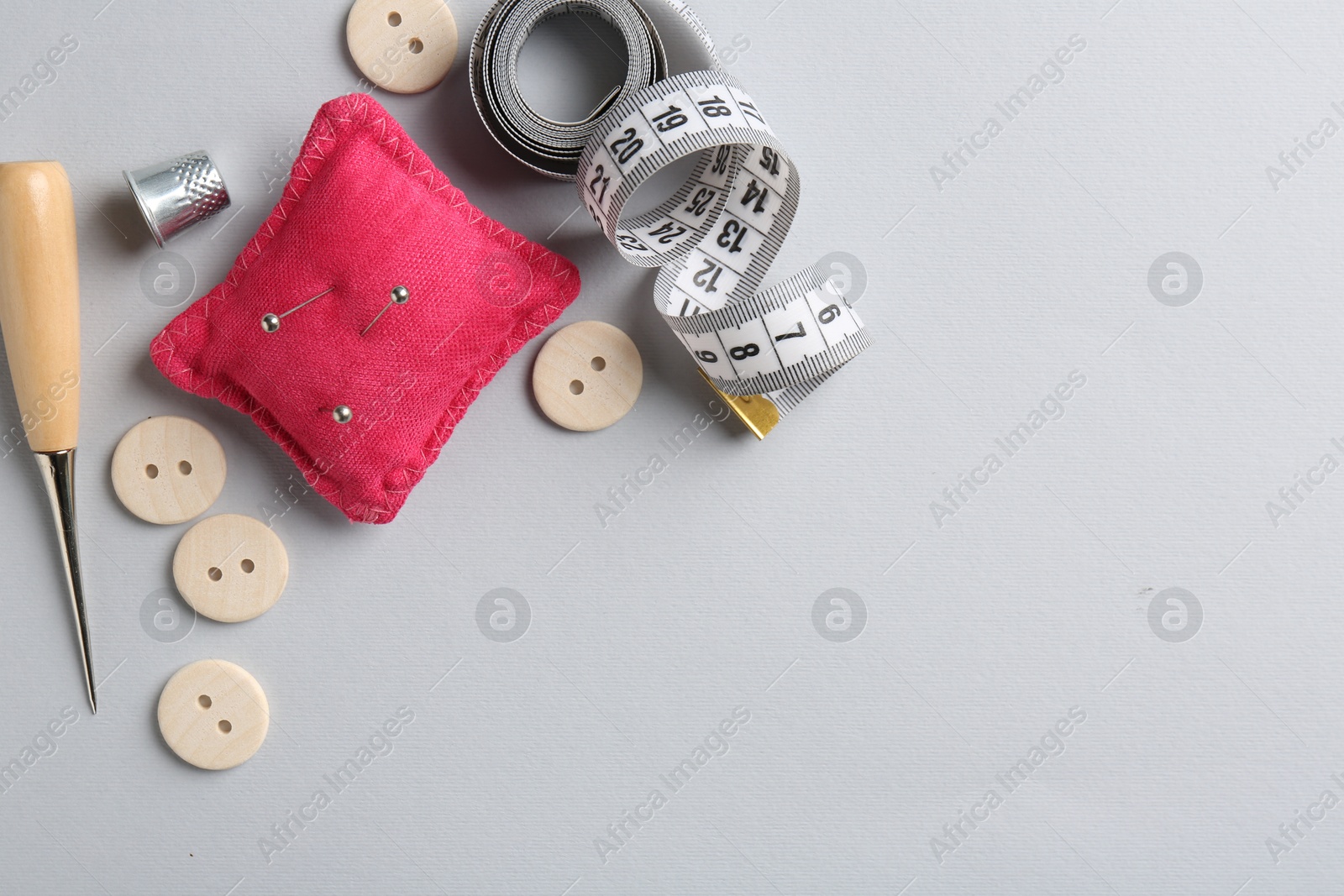 Photo of Different sewing supplies on light grey background, flat lay. Space for text