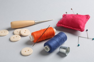 Photo of Different sewing supplies on light grey background, closeup