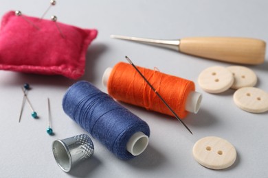 Photo of Different sewing supplies on light grey background, closeup