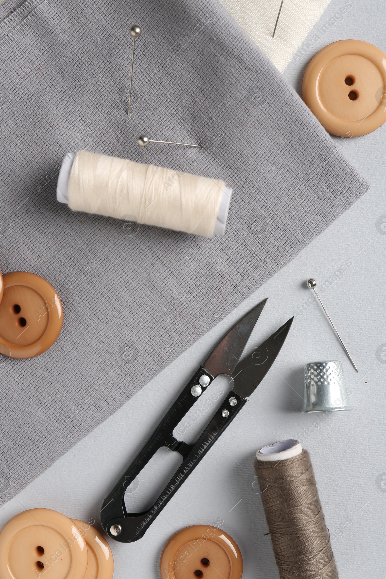 Photo of Different sewing supplies and fabric on light grey background, flat lay