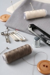 Photo of Different sewing supplies on light grey background, closeup