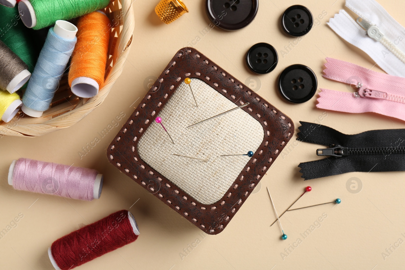 Photo of Different sewing supplies on beige background, flat lay