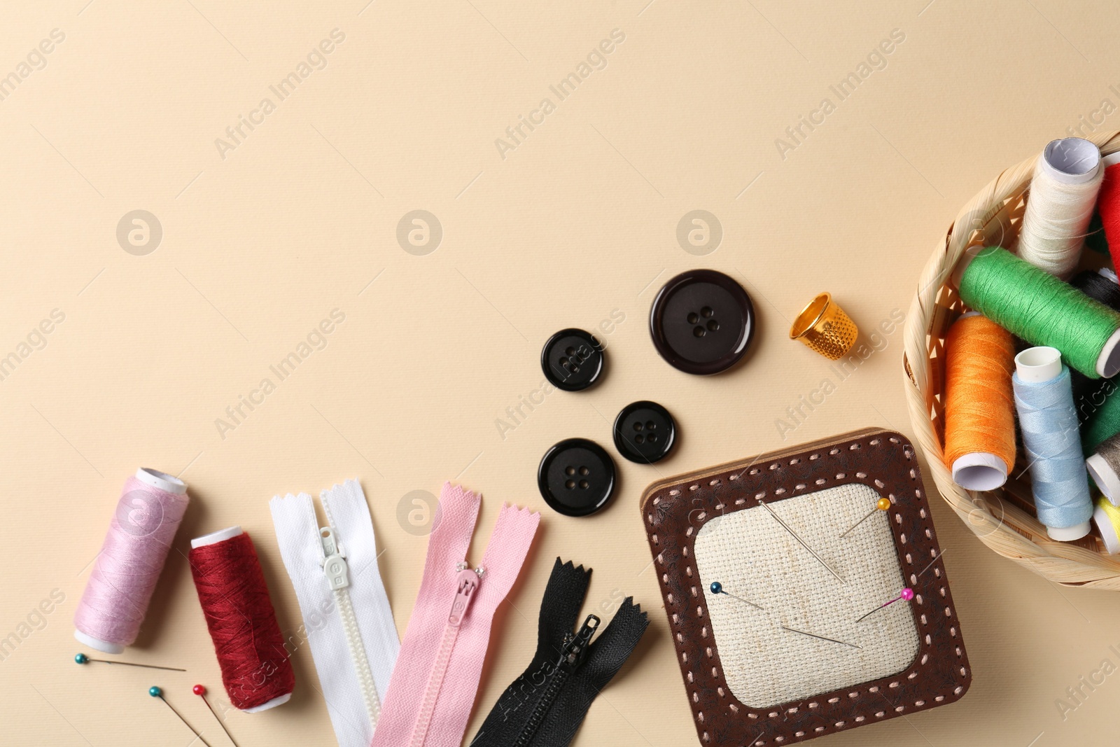 Photo of Different sewing supplies on beige background, flat lay. Space for text