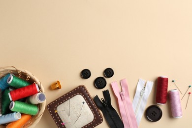 Photo of Different sewing supplies on beige background, flat lay. Space for text