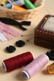 Photo of Different sewing supplies on beige background, closeup