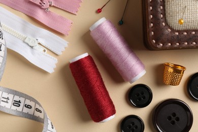 Photo of Different sewing supplies on beige background, flat lay