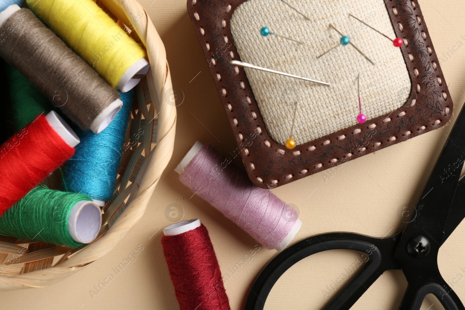 Photo of Different sewing supplies on beige background, flat lay