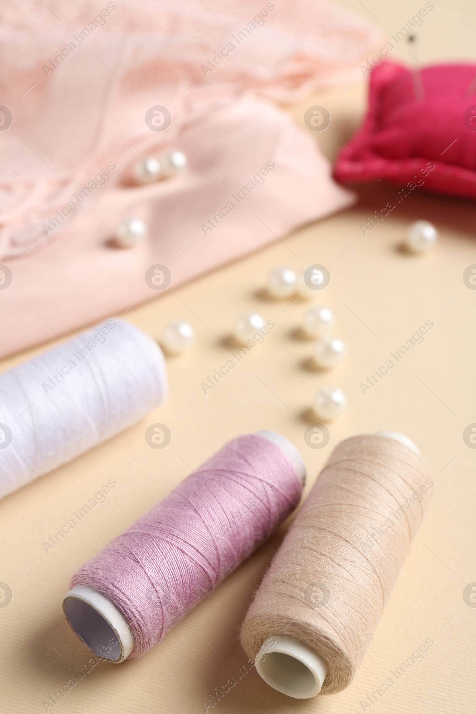 Photo of Different sewing supplies on beige background, closeup