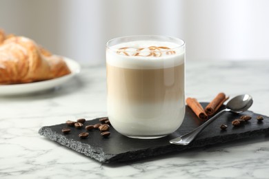 Photo of Tasty latte macchiato in glass on marble table, closeup. Coffee drink