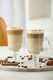 Photo of Tasty latte macchiato, coffee beans and cinnamon sticks on white table