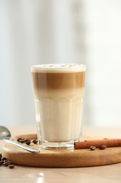 Photo of Tasty latte macchiato in glass on wooden table, closeup. Space for text