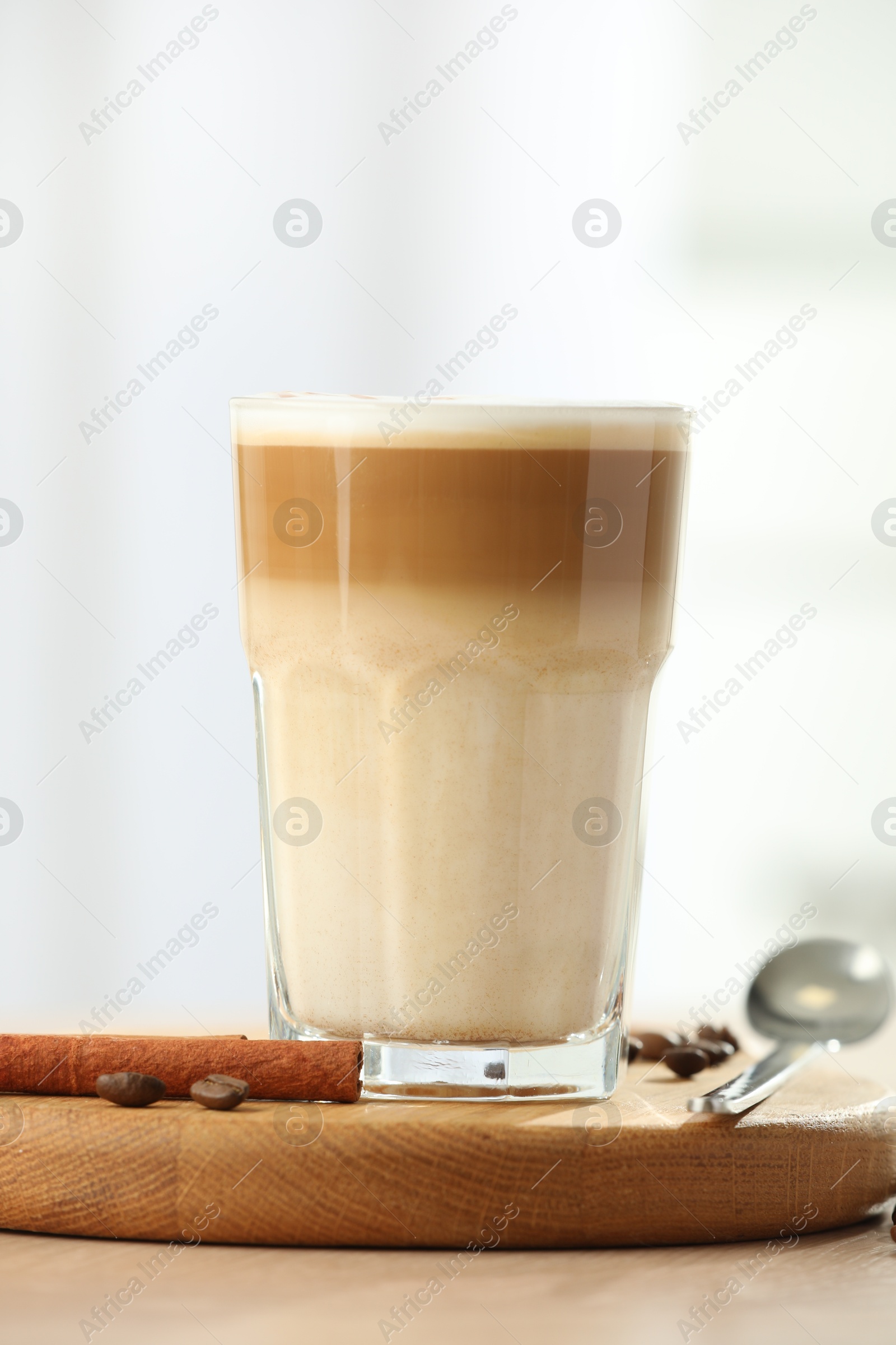 Photo of Tasty latte macchiato in glass on wooden table, closeup