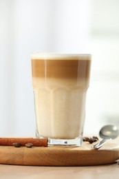 Photo of Tasty latte macchiato in glass on wooden table, closeup