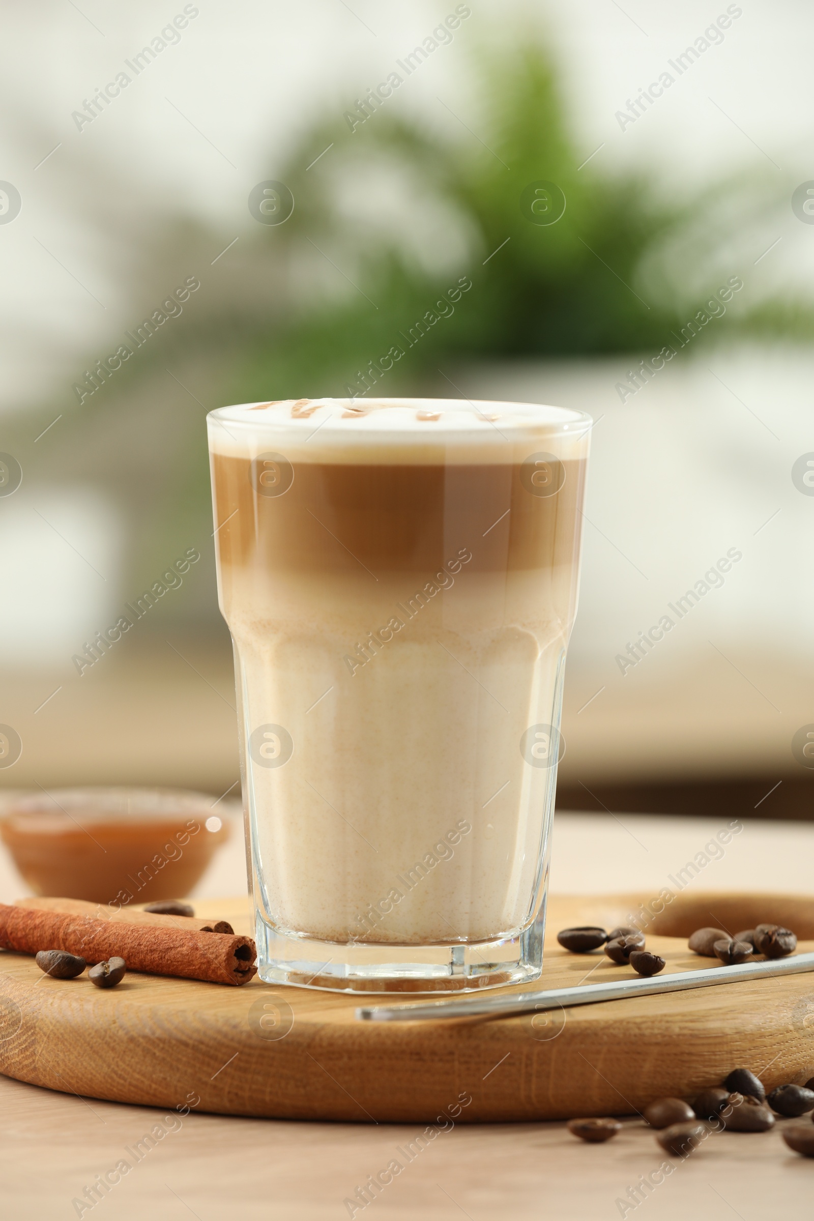 Photo of Tasty latte macchiato in glass on wooden table, closeup