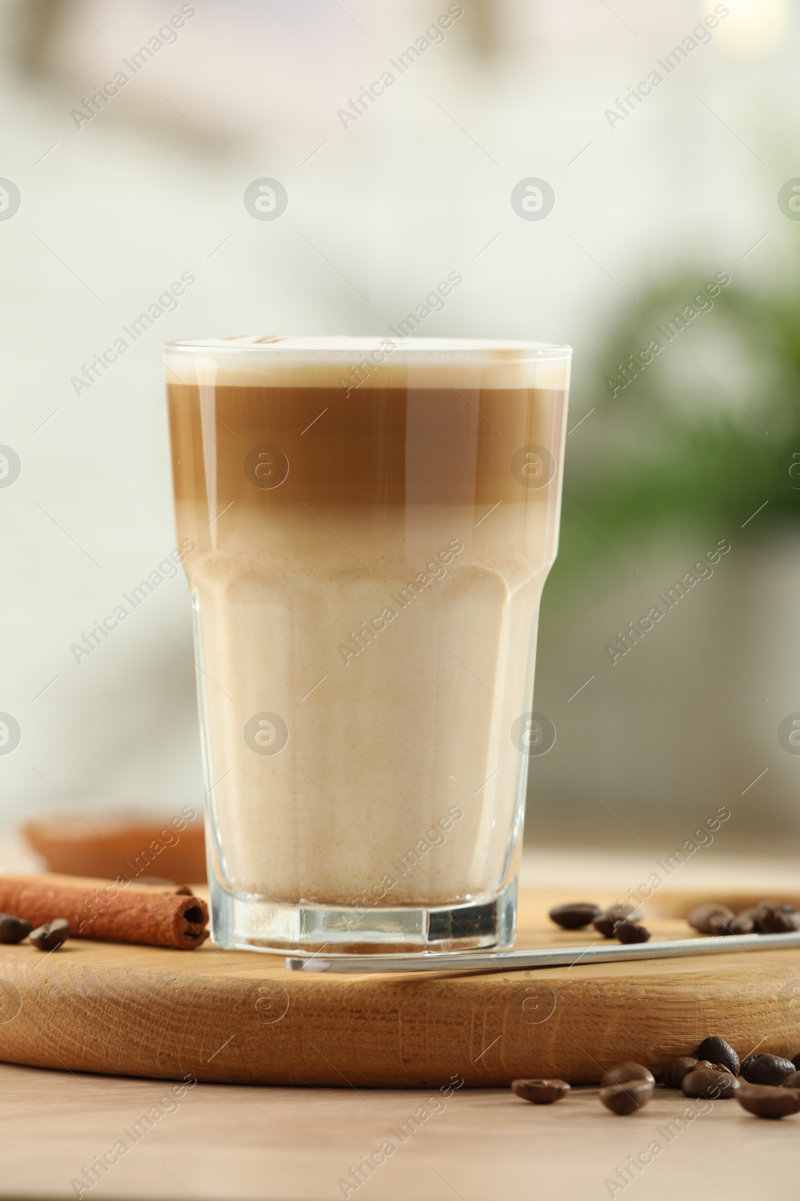 Photo of Tasty latte macchiato in glass on wooden table, closeup