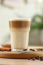 Photo of Tasty latte macchiato in glass on wooden table, closeup