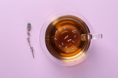 Aromatic lavender tea in glass cup and dry flower on pink background, top view