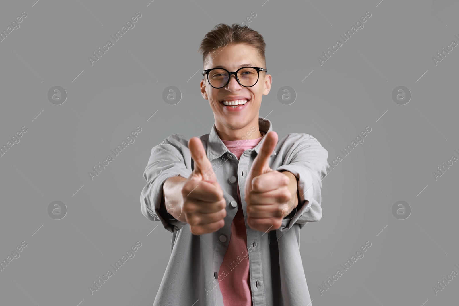 Photo of Happy man showing thumbs up on grey background. Like gesture