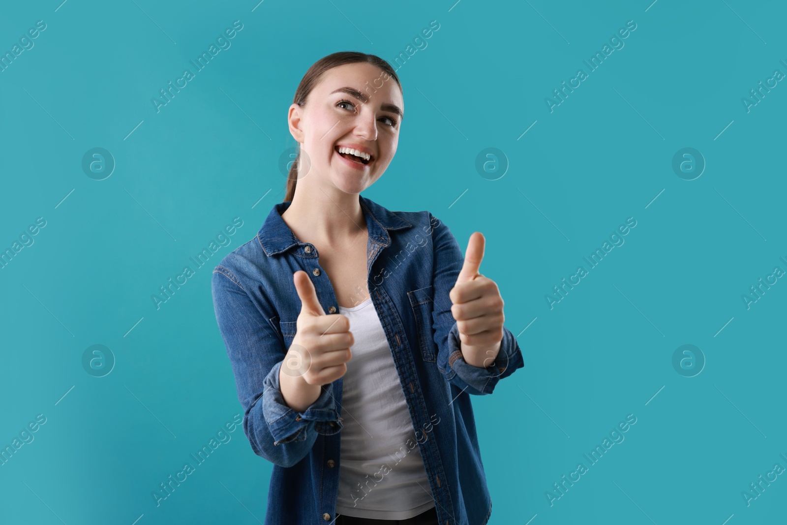 Photo of Happy woman showing thumbs up on light blue background. Like gesture