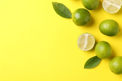 Photo of Fresh limes and leaves on yellow background. Space for text