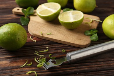 Photo of Lime zest, zester, mint leaves and fresh fruits on wooden table, closeup