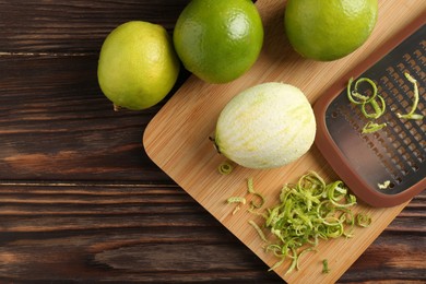 Photo of Lime zest, grater and fresh fruits on wooden table, flat lay. Space for text