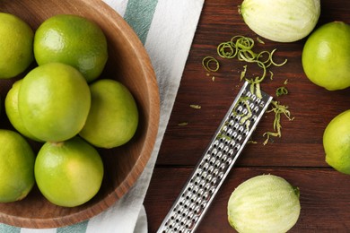 Photo of Lime zest, grater and fresh fruits on wooden table, flat lay