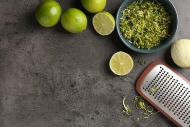 Photo of Lime zest, fresh fruits and grater on grey textured table. Space for text