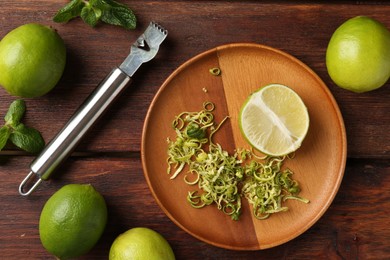 Photo of Lime zest, zester, mint leaves and fresh fruits on wooden table, flat lay