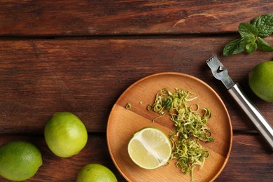 Photo of Lime zest, zester, mint leaves and fresh fruits on wooden table, flat lay. Space for text