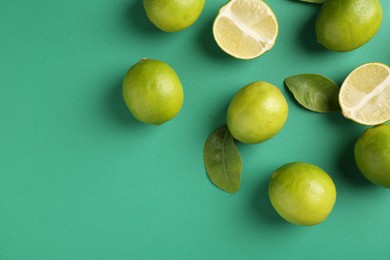 Photo of Fresh limes and leaves on green background. Space for text