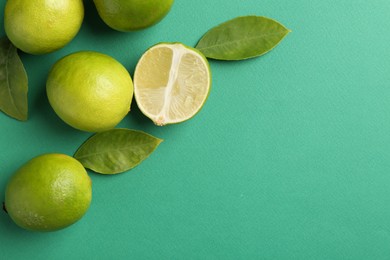 Photo of Fresh limes and leaves on green background. Space for text