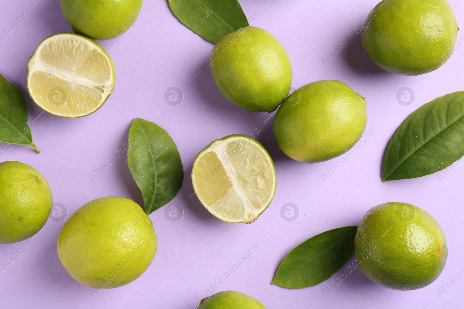 Photo of Fresh limes and leaves on violet background