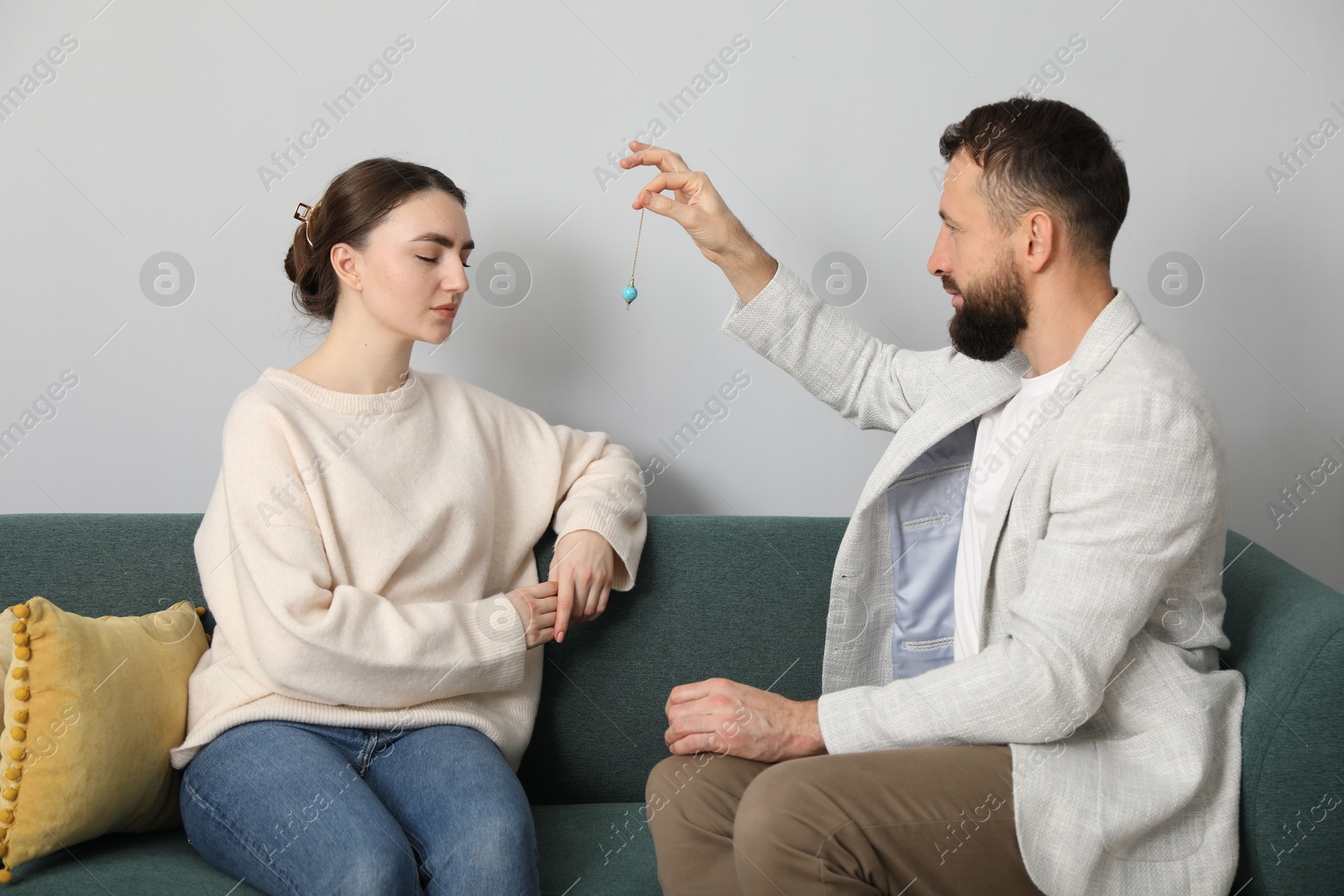 Photo of Psychologist using pendulum while working with patient during hypnosis session indoors