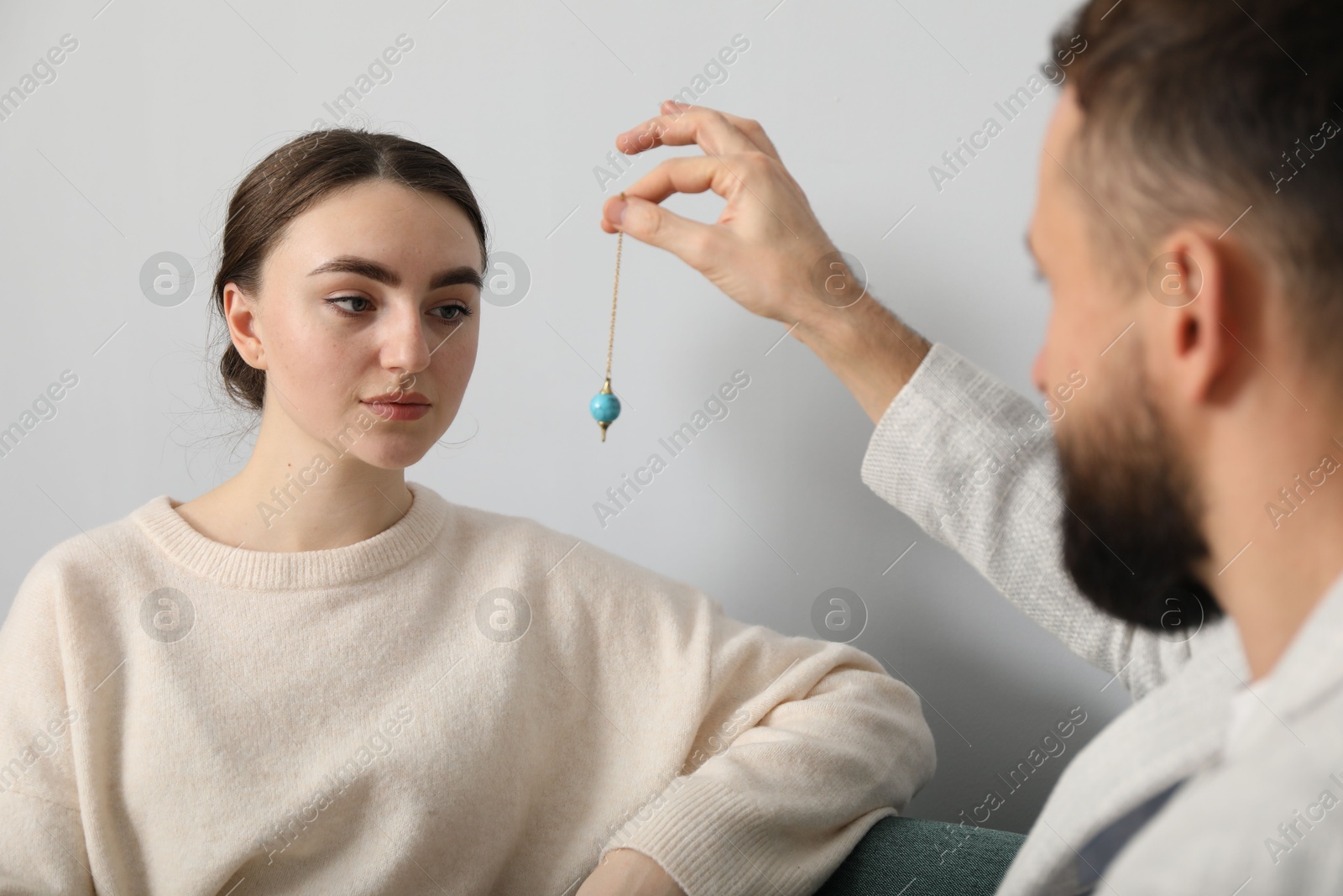 Photo of Psychologist using pendulum while working with patient during hypnosis session indoors