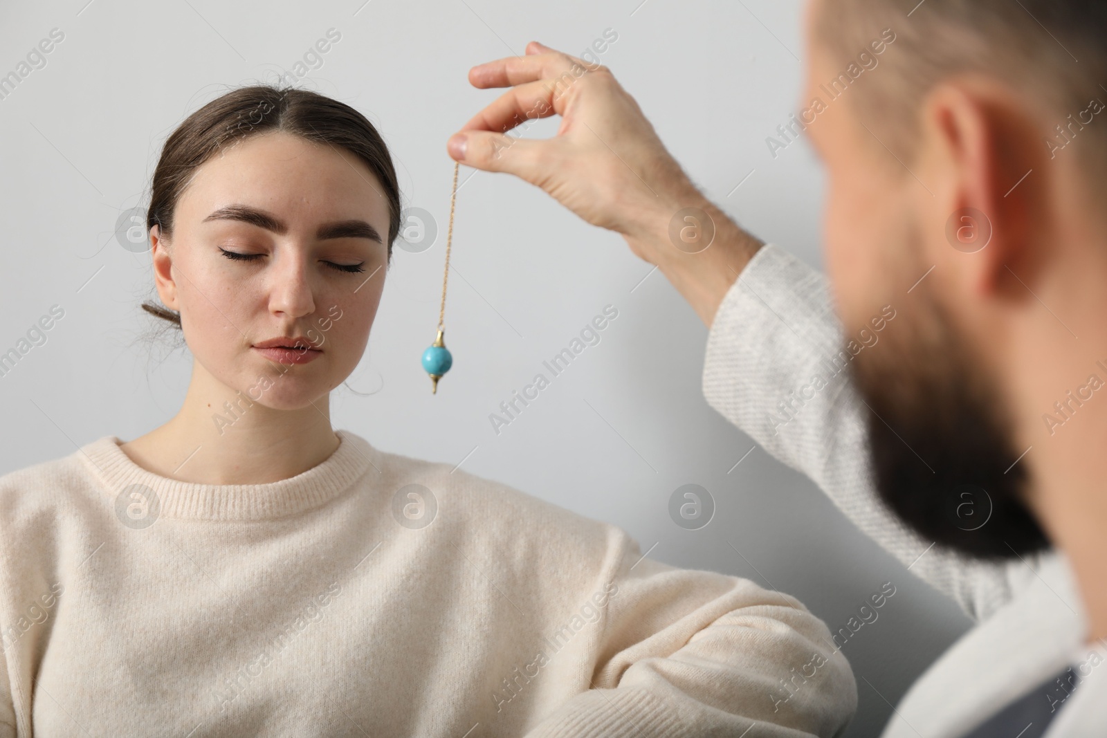 Photo of Psychologist using pendulum while working with patient during hypnosis session indoors