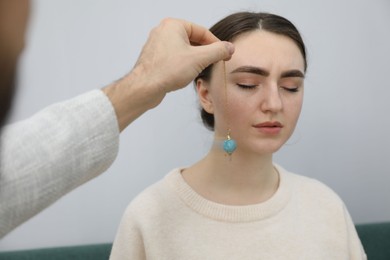 Photo of Psychologist using pendulum while working with patient during hypnosis session indoors, closeup