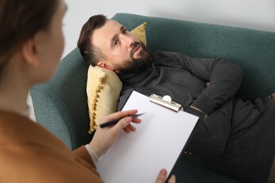 Photo of Psychologist working with patient during hypnosis session indoors