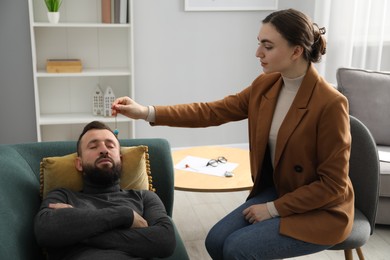 Photo of Psychologist using pendulum while working with patient during hypnosis session indoors